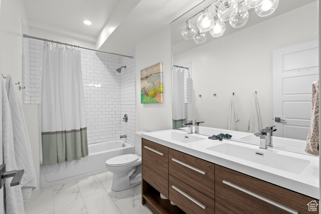 Full bathroom featuring double vanity, shower / tub combo with curtain, toilet, marble look tile flooring, and recessed lighting