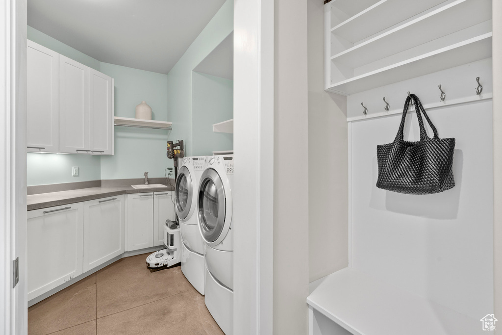 Laundry room with washer and clothes dryer, light tile patterned floors, and cabinet space
