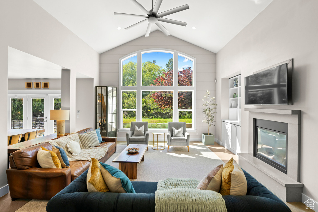 Living room with a ceiling fan, a high end fireplace, baseboards, high vaulted ceiling, and built in features