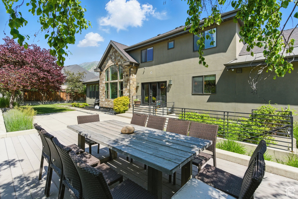 Wooden terrace with outdoor dining space, a mountain view, and french doors