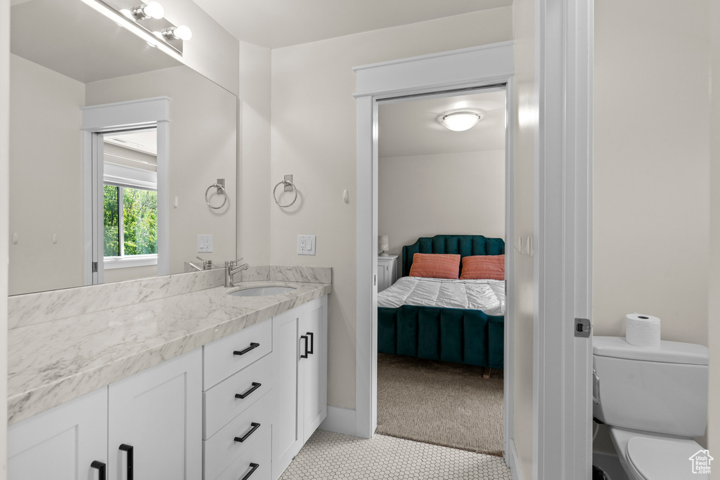 Bathroom with ensuite bathroom, vanity, toilet, and tile patterned floors