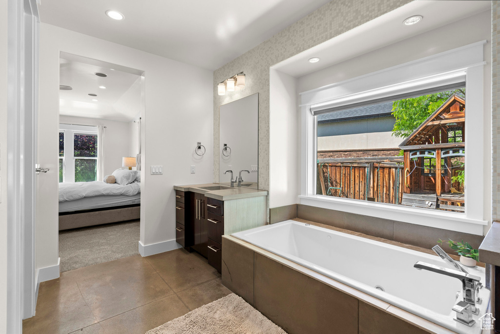 Ensuite bathroom with vanity, a whirlpool tub, recessed lighting, and baseboards