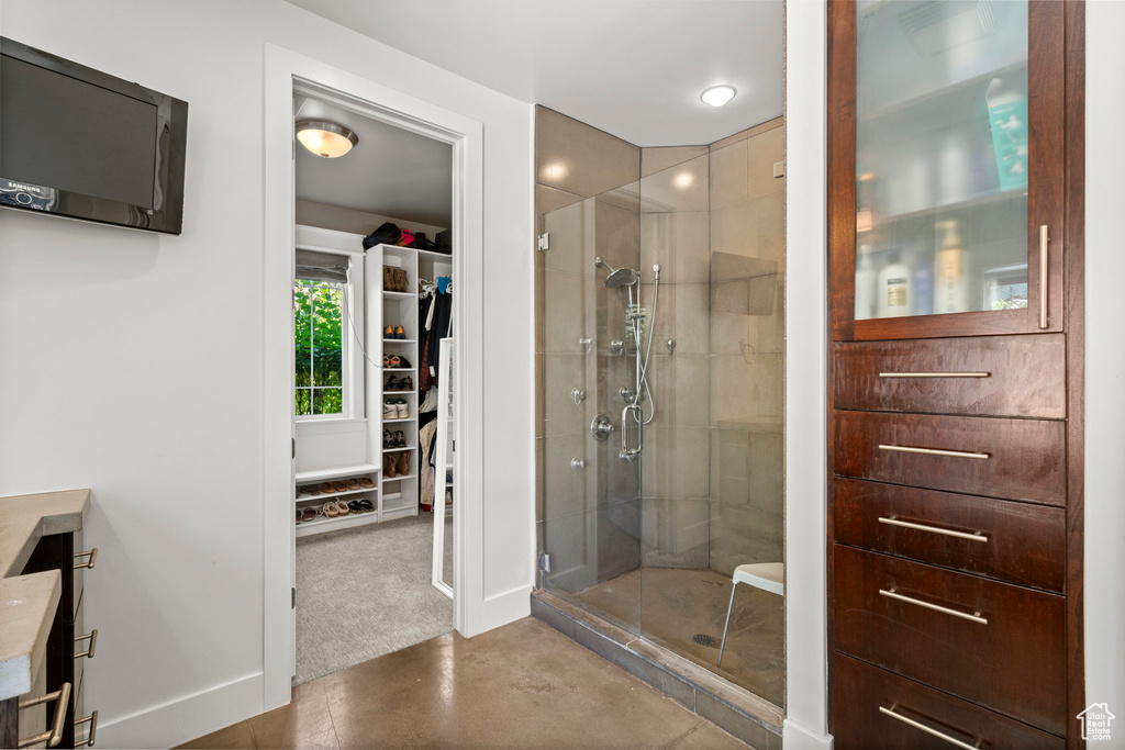 Bathroom featuring a stall shower, vanity, baseboards, and a spacious closet