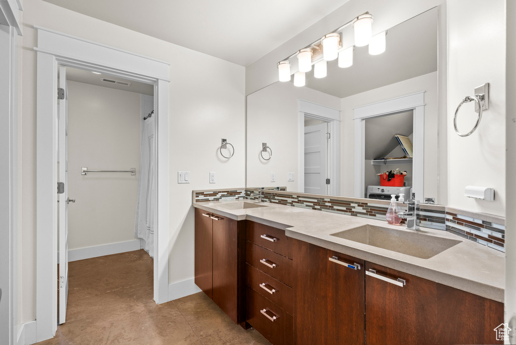 Bathroom featuring backsplash, double vanity, and baseboards