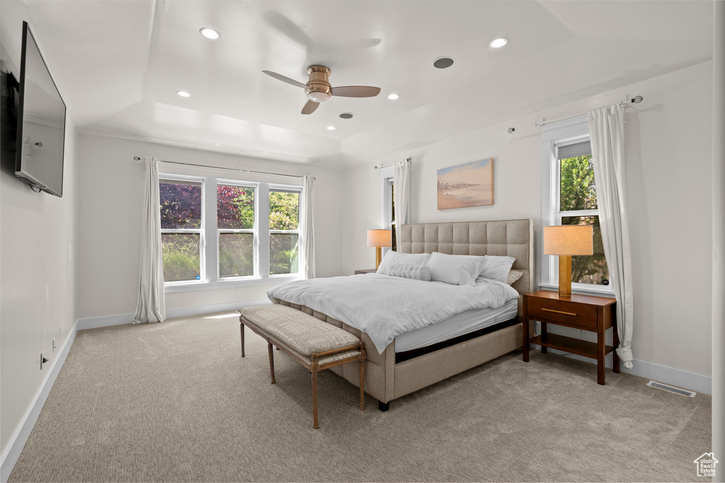 Bedroom featuring light colored carpet, multiple windows, a raised ceiling, and recessed lighting