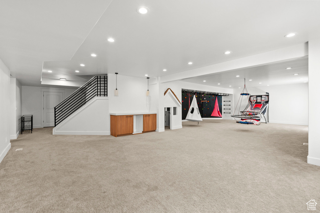 Finished basement with recessed lighting, light carpet, stairway, baseboards, and bar