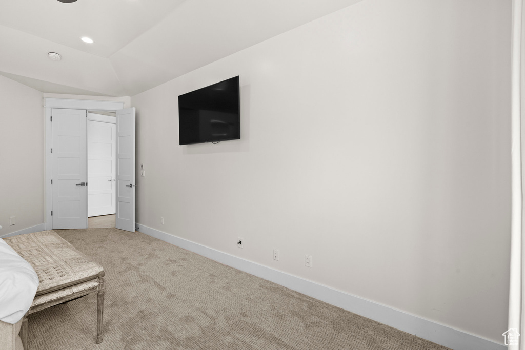 Unfurnished bedroom featuring carpet flooring, baseboards, and lofted ceiling