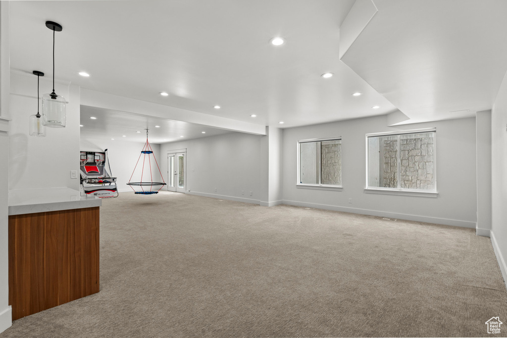 Unfurnished living room featuring light carpet, recessed lighting, baseboards, and healthy amount of natural light