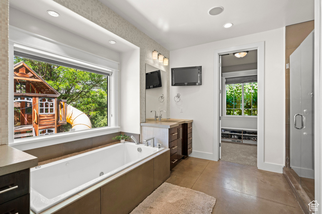 Bathroom featuring vanity, a tub with jets, recessed lighting, baseboards, and a stall shower