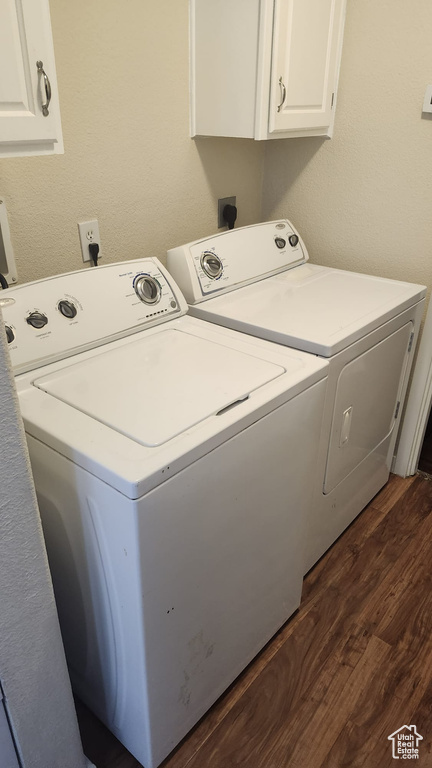 Laundry area featuring separate washer and dryer, cabinet space, and dark wood finished floors