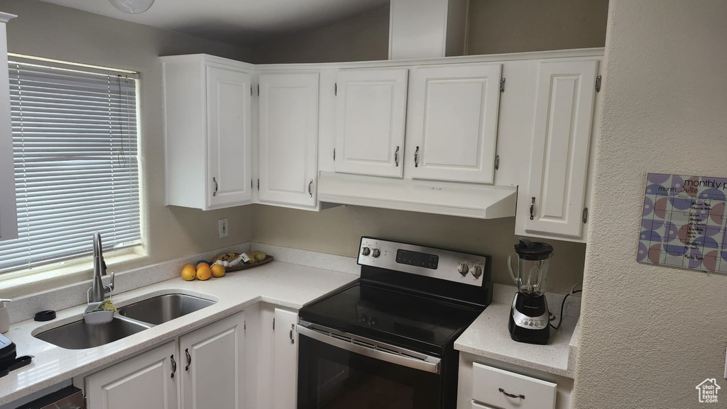 Kitchen featuring stainless steel appliances, a sink, under cabinet range hood, white cabinetry, and light countertops