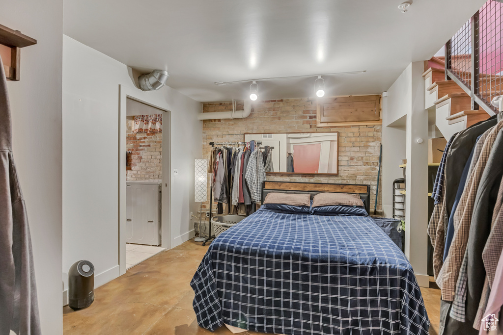 Bedroom featuring rail lighting, baseboards, and concrete floors