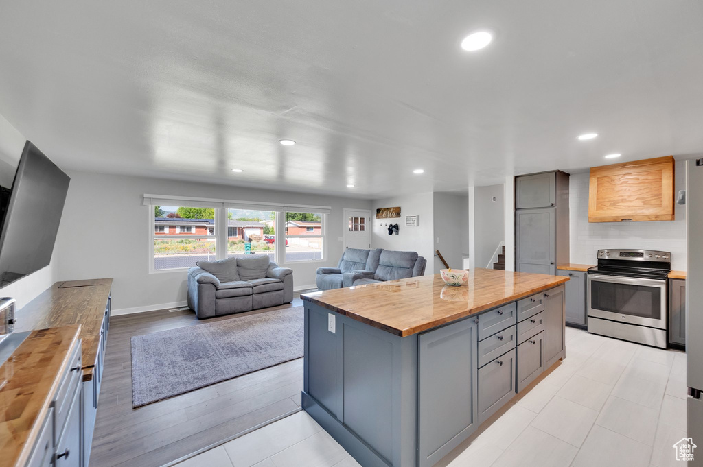 Kitchen with butcher block countertops, stainless steel range with electric stovetop, gray cabinets, a kitchen island, and recessed lighting