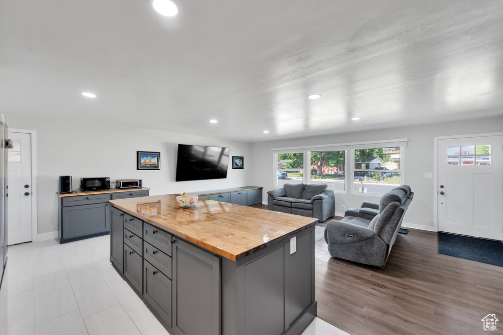Kitchen featuring butcher block countertops, gray cabinetry, open floor plan, recessed lighting, and baseboards