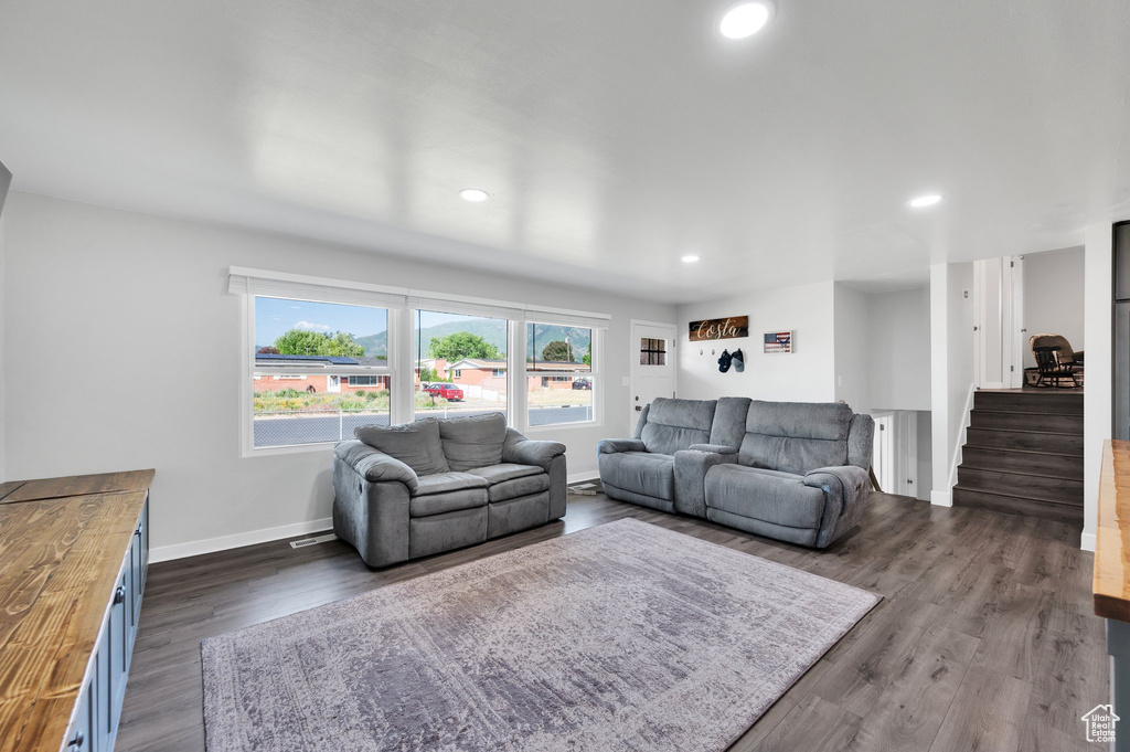 Living area with baseboards, dark wood-type flooring, and recessed lighting
