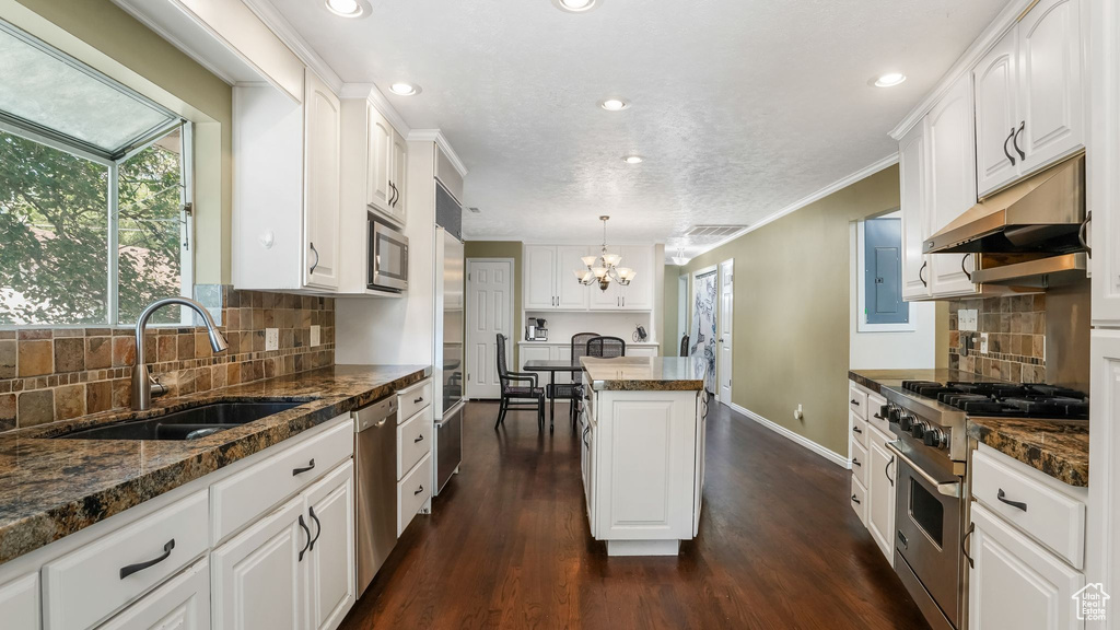 Kitchen featuring stainless steel appliances, a sink, a center island, a chandelier, and white cabinetry