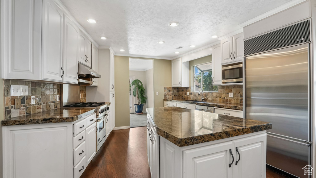 Kitchen with premium appliances, a kitchen island, a sink, dark wood-style floors, and recessed lighting
