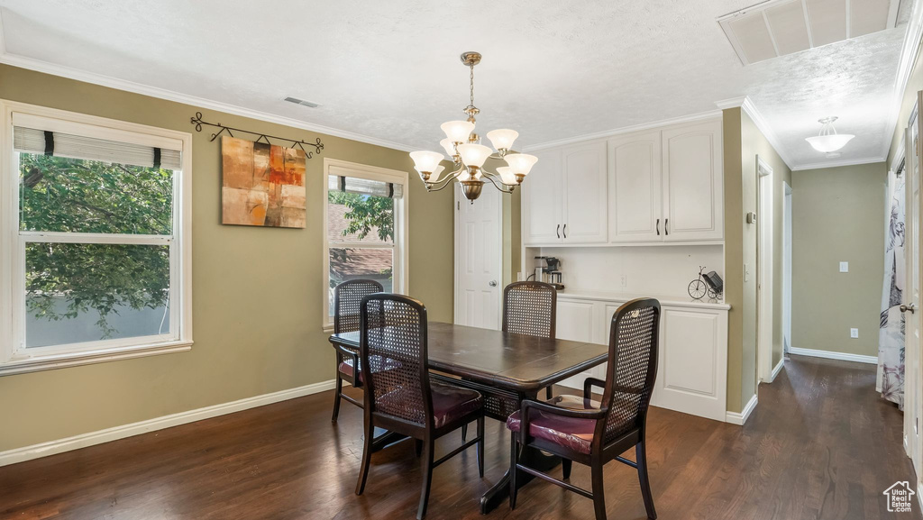 Dining area featuring a chandelier, baseboards, dark wood-style flooring, and crown molding