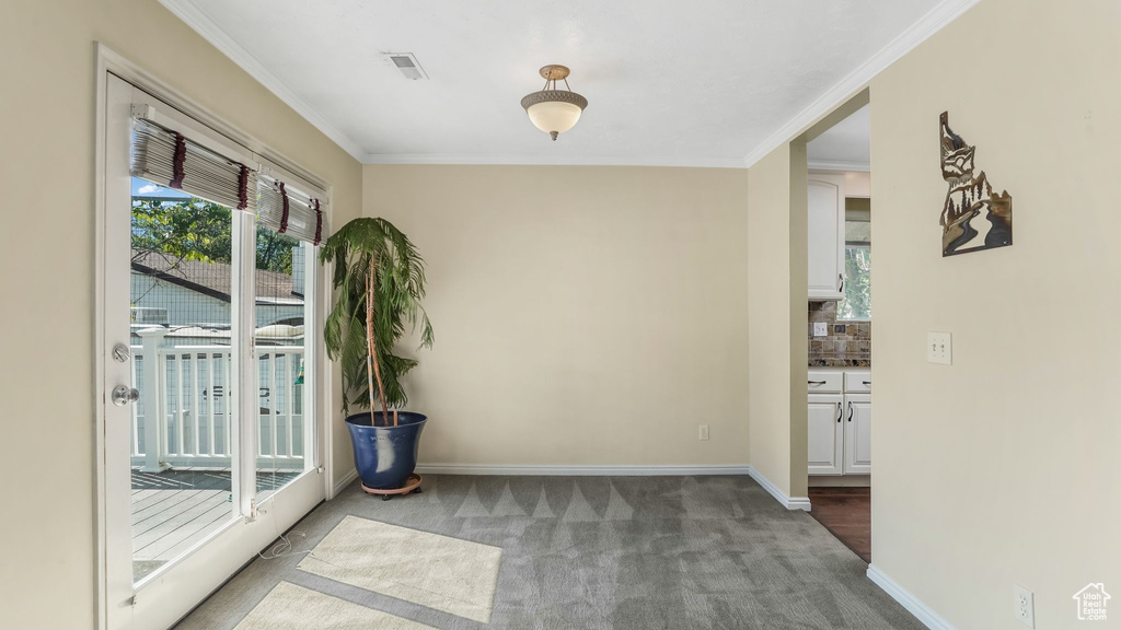 Empty room featuring carpet floors, ornamental molding, and baseboards