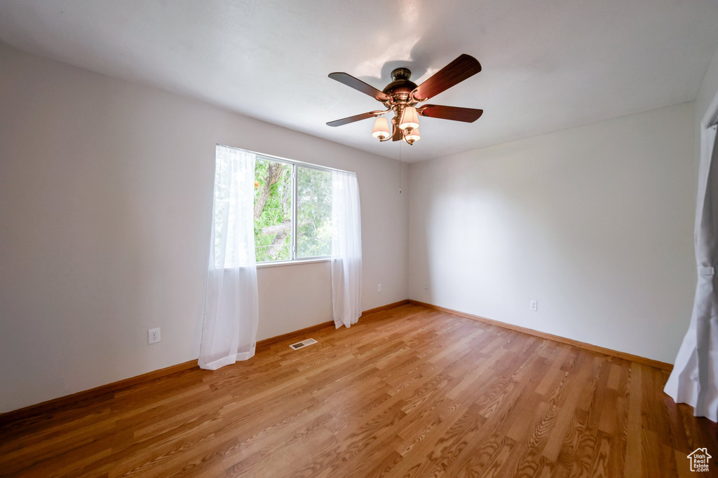 Unfurnished room featuring baseboards, light wood-style floors, and ceiling fan