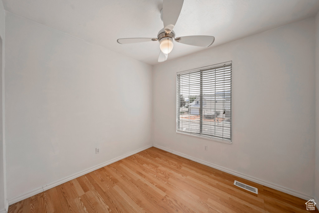 Spare room featuring light wood-style floors, ceiling fan, and baseboards