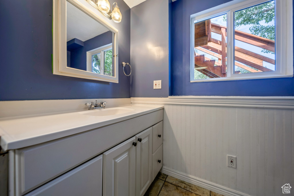 Bathroom featuring vanity, wainscoting, and tile patterned flooring