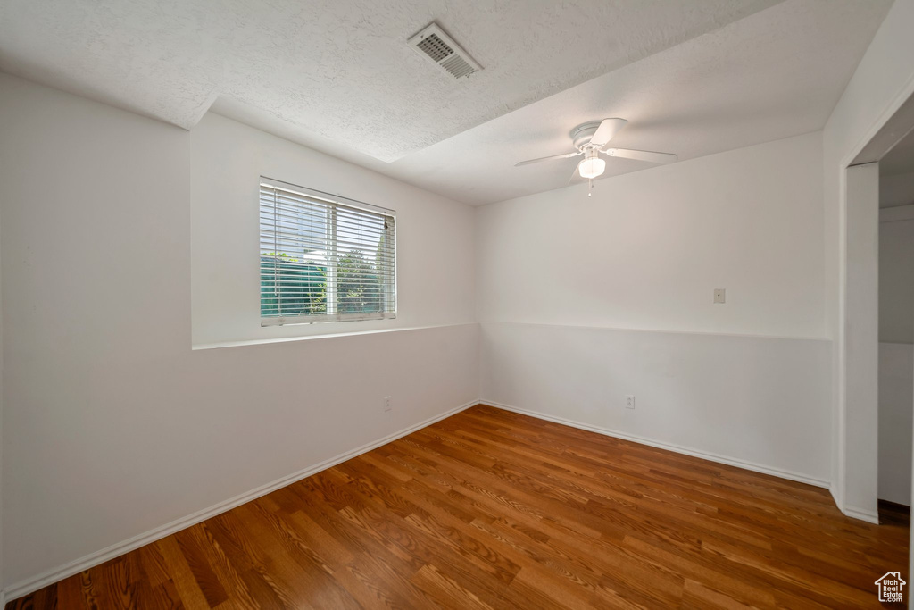 Unfurnished room featuring wood finished floors, a ceiling fan, a textured ceiling, and baseboards