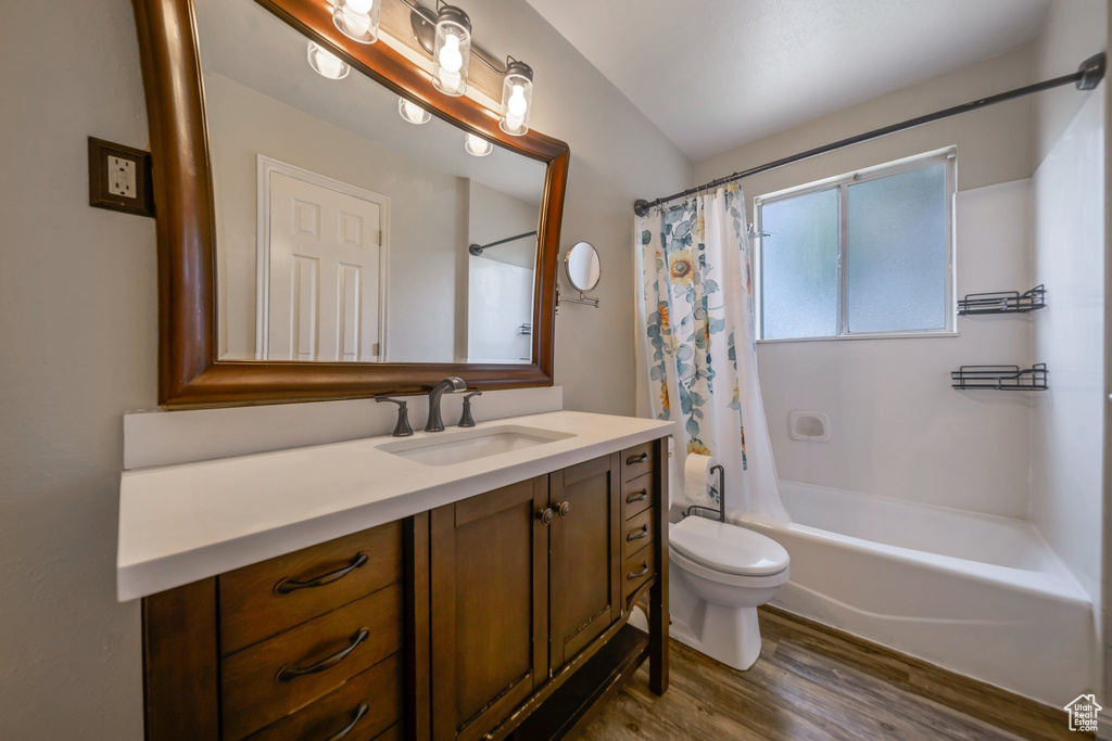 Bathroom featuring vanity, toilet, wood finished floors, and shower / bath combo with shower curtain