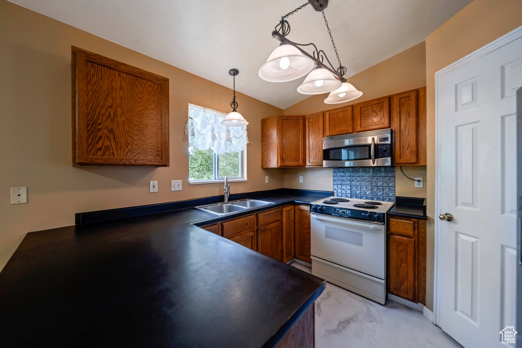 Kitchen with electric stove, a sink, stainless steel microwave, brown cabinetry, and lofted ceiling