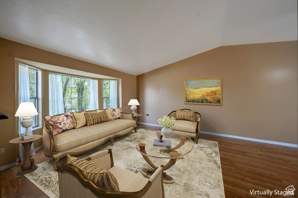 Living room featuring vaulted ceiling, wood finished floors, and baseboards
