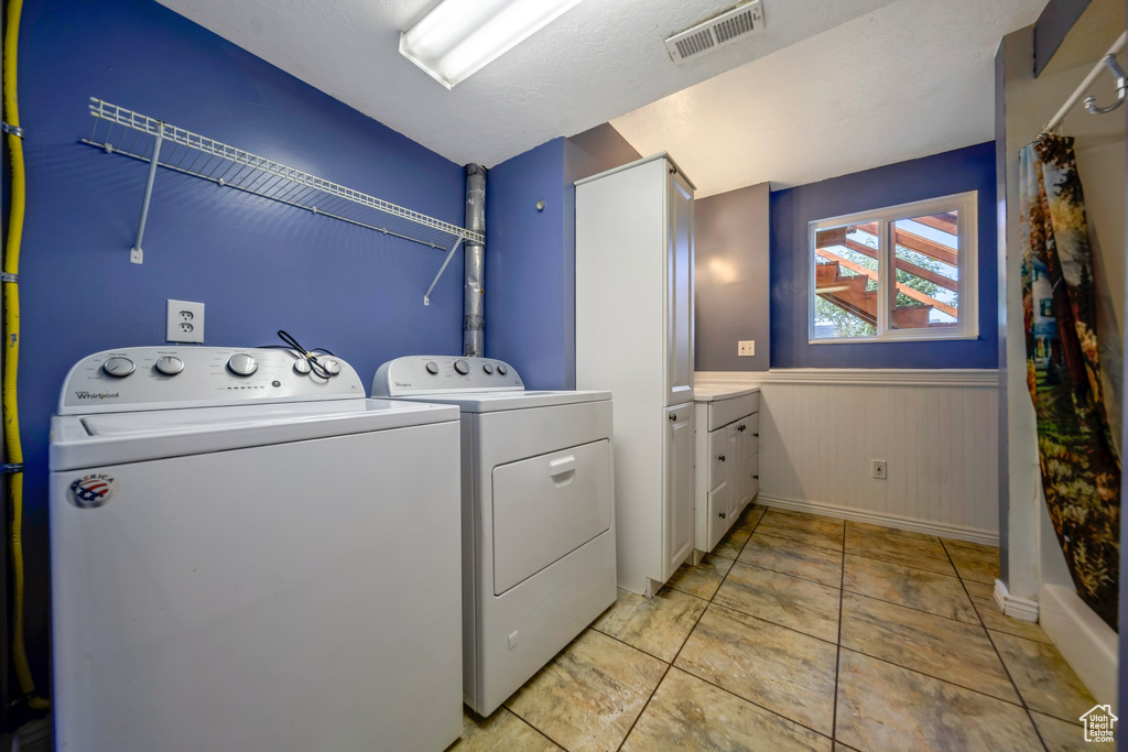 Laundry room with washer and dryer, wainscoting, and baseboards