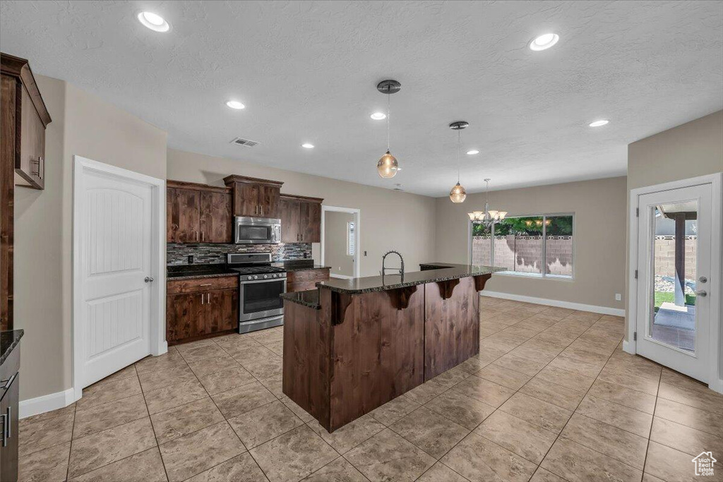 Kitchen featuring appliances with stainless steel finishes, a kitchen breakfast bar, baseboards, dark brown cabinets, and recessed lighting