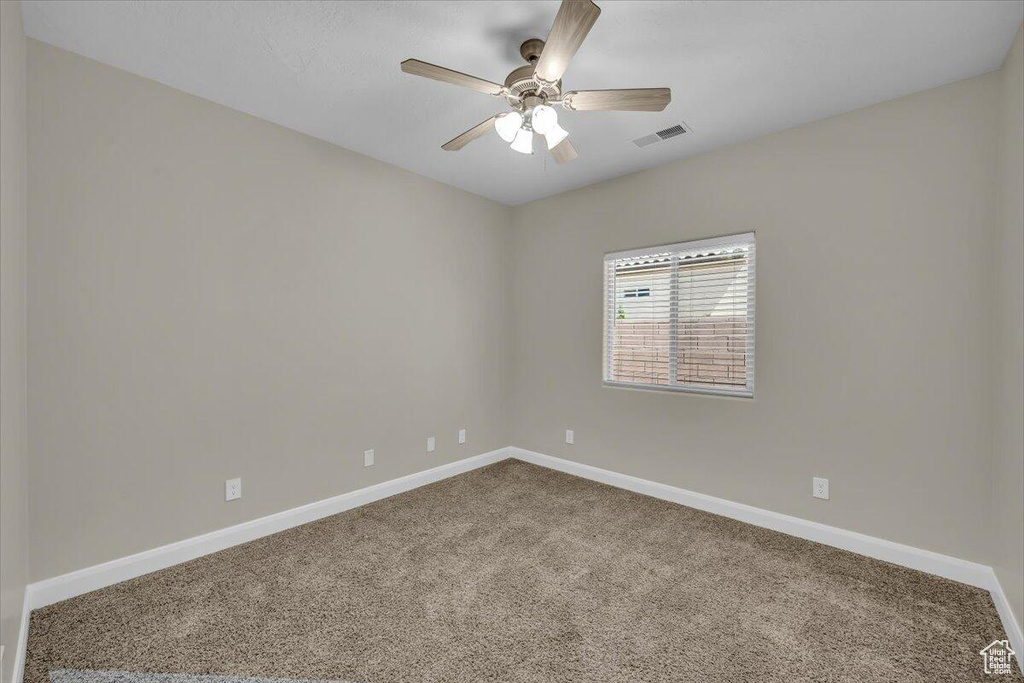 Carpeted empty room featuring baseboards and ceiling fan