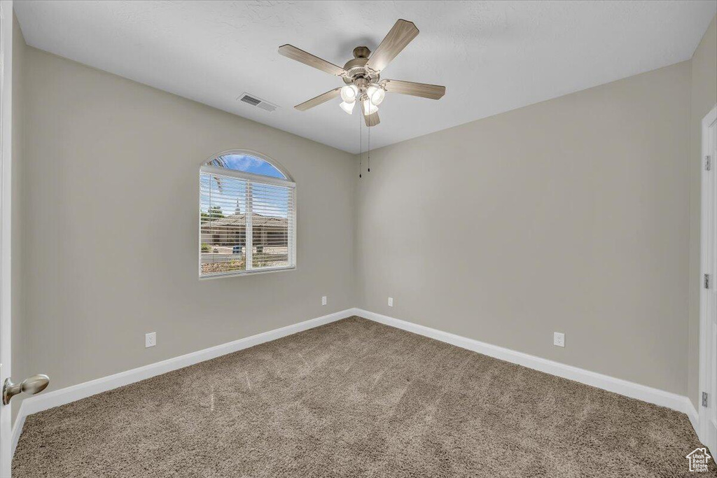 Spare room with a ceiling fan, carpet, and baseboards