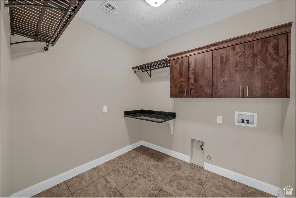 Laundry area with baseboards, cabinet space, washer hookup, hookup for a gas dryer, and light tile patterned floors