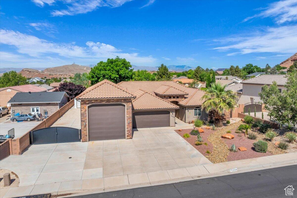 Mediterranean / spanish-style home with a gate, a garage, concrete driveway, a tile roof, and a mountain view