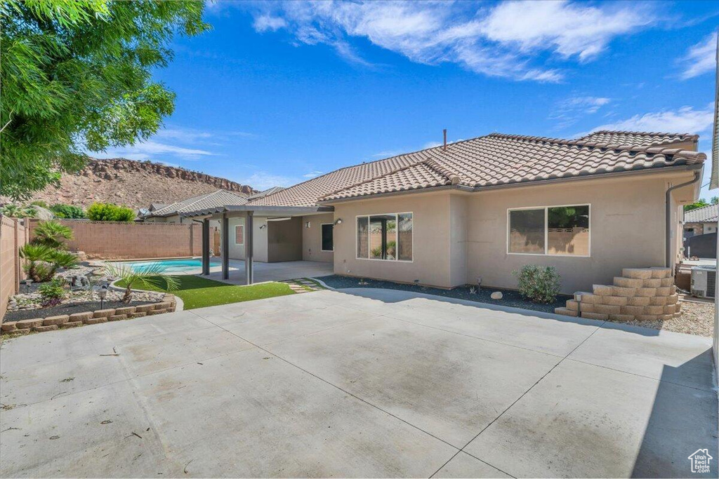 Back of house with a tile roof, stucco siding, a fenced backyard, and a patio area