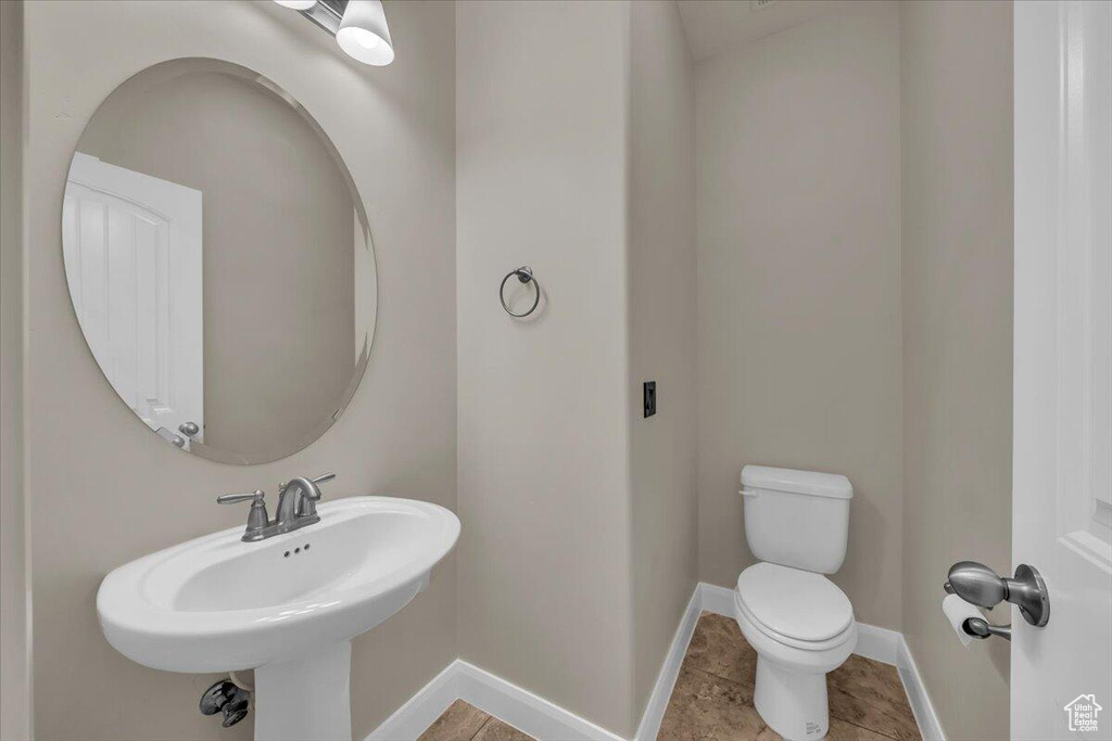Half bathroom featuring toilet, baseboards, and a sink