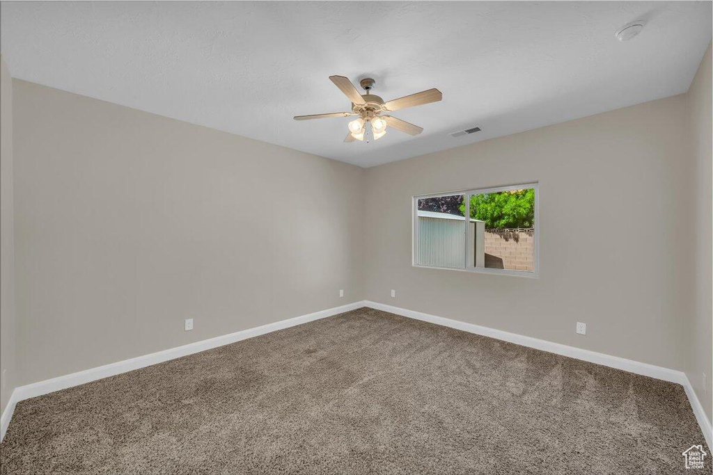 Spare room featuring carpet flooring, ceiling fan, and baseboards