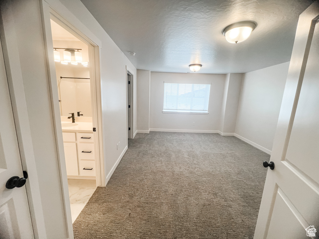 Unfurnished room featuring carpet flooring, baseboards, a sink, a textured ceiling, and a smoke detector