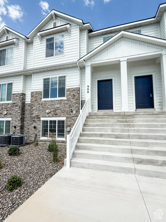 View of front of home with stone siding, board and batten siding, and central air condition unit
