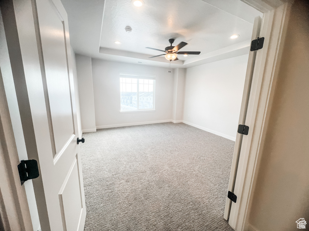 Carpeted spare room with a tray ceiling, recessed lighting, a ceiling fan, baseboards, and a smoke detector