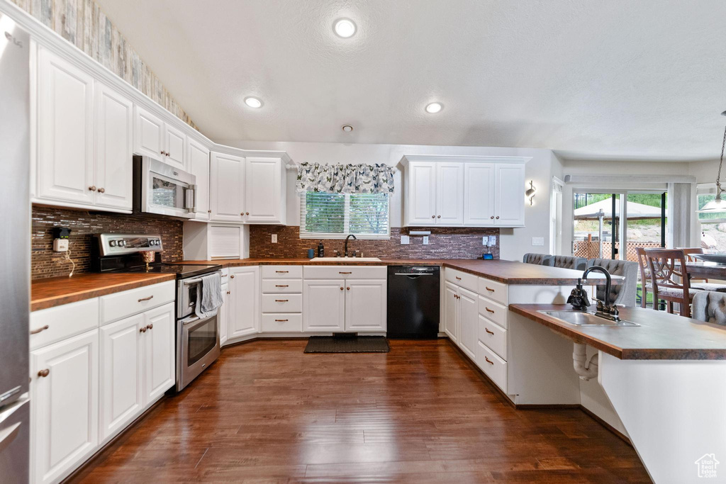 Kitchen with stainless steel appliances, a sink, a peninsula, healthy amount of natural light, and recessed lighting