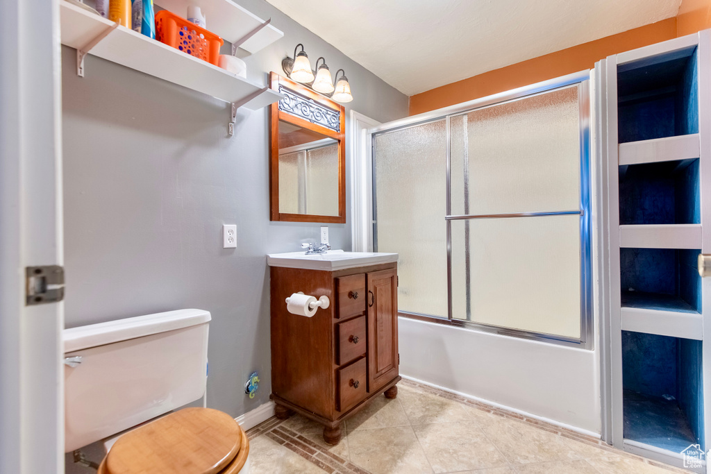 Bathroom featuring vanity, shower / bath combination with glass door, toilet, baseboards, and tile patterned floors