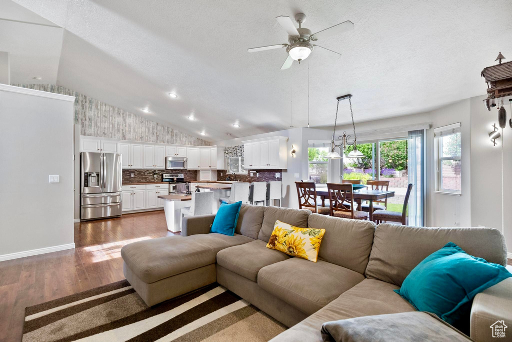 Living area featuring lofted ceiling, wood finished floors, a ceiling fan, and baseboards
