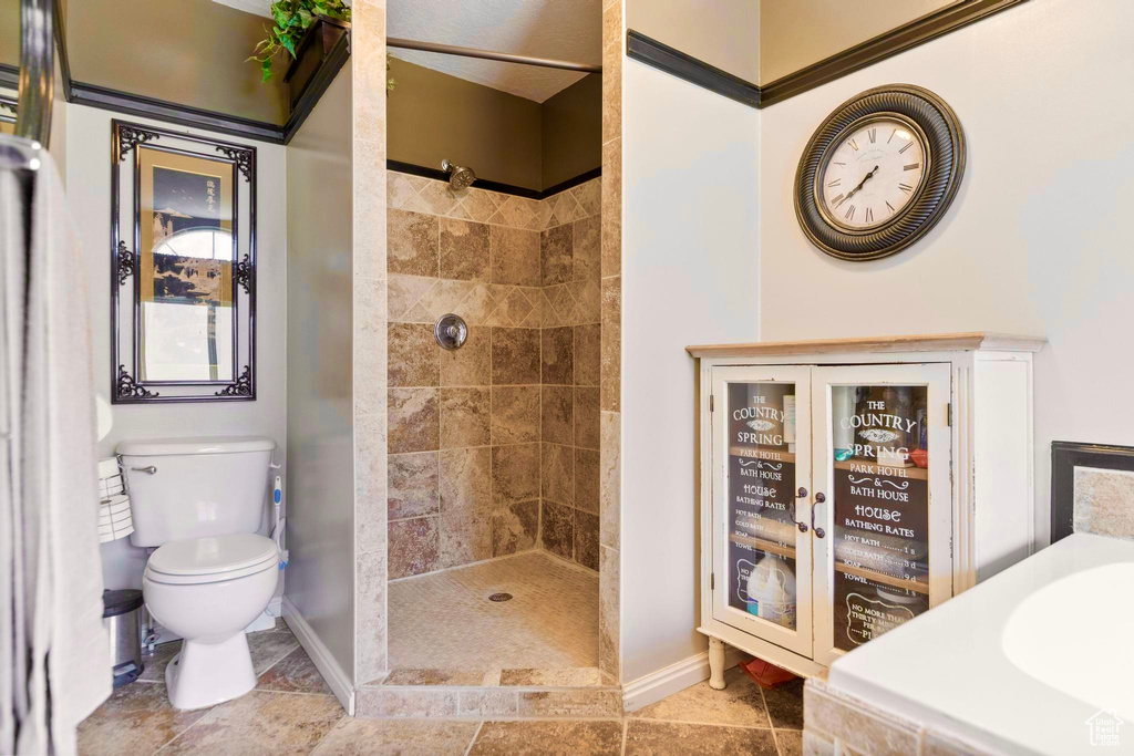 Bathroom featuring baseboards, toilet, and tiled shower