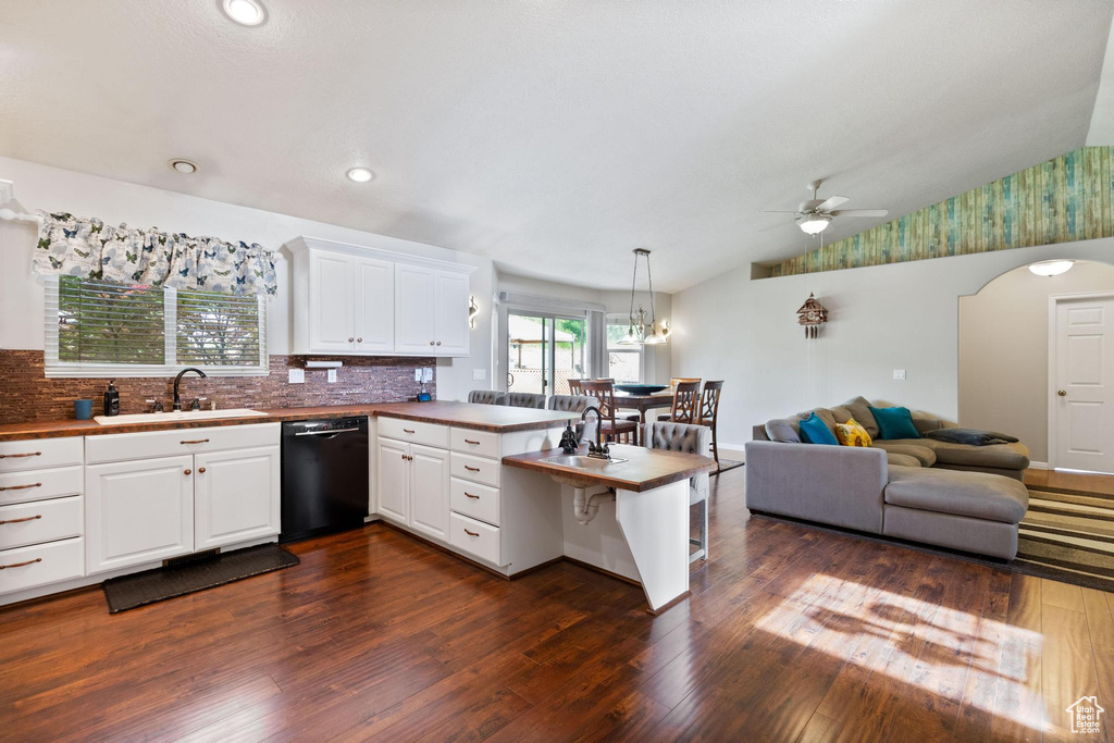 Kitchen with dishwasher, a peninsula, a sink, a ceiling fan, and dark wood-type flooring
