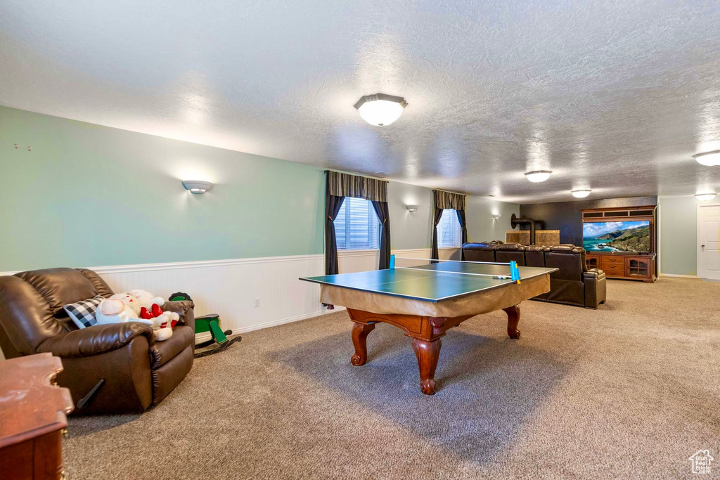 Game room featuring carpet floors, a textured ceiling, and wainscoting
