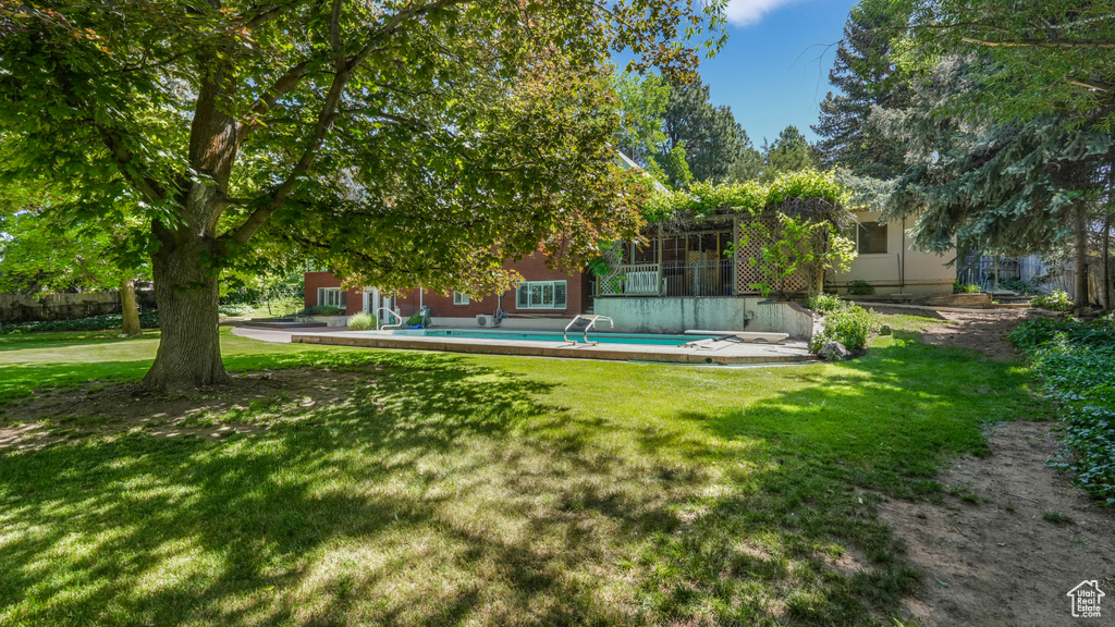 View of grassy yard with an outdoor pool and a sunroom