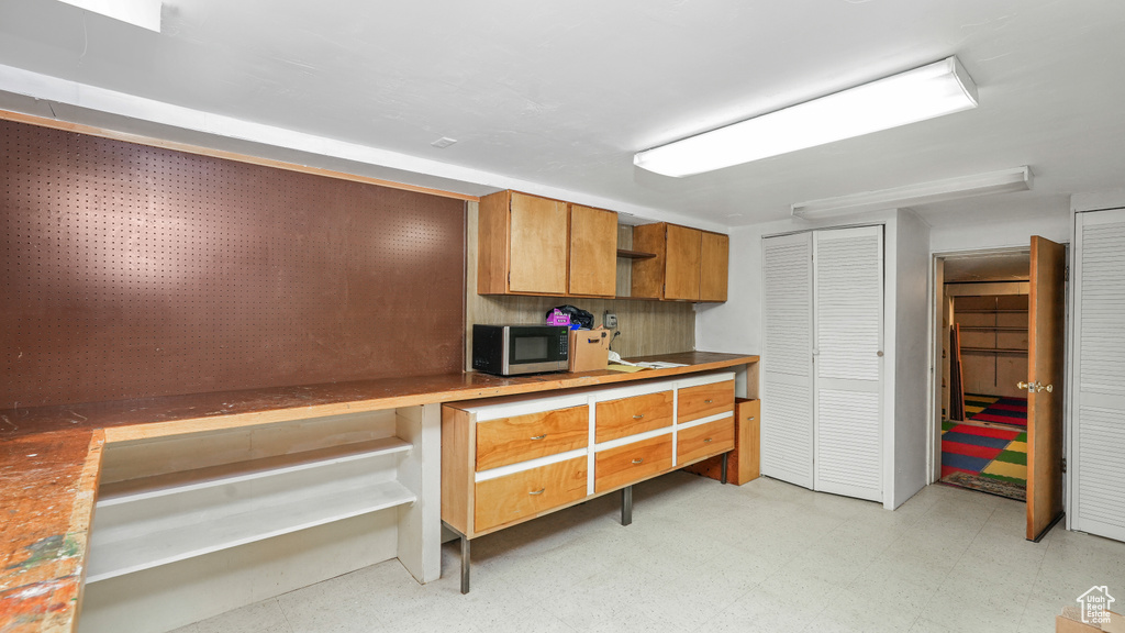 Kitchen with stainless steel microwave, light floors, open shelves, and brown cabinets